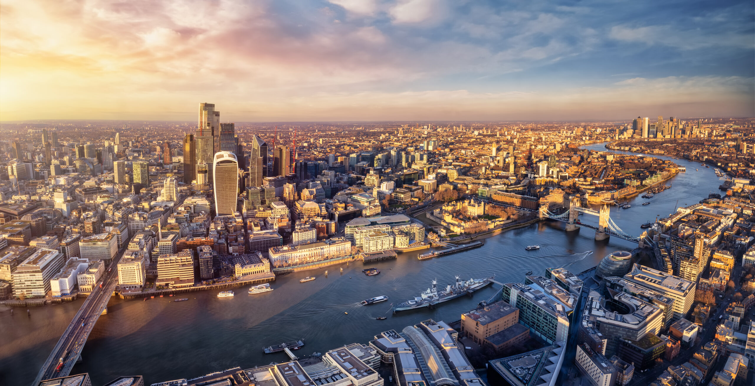 Panoramic sunset view over the skyline of the City of London, England, down the River Thames with Tower Bridge and Canary Wharf district